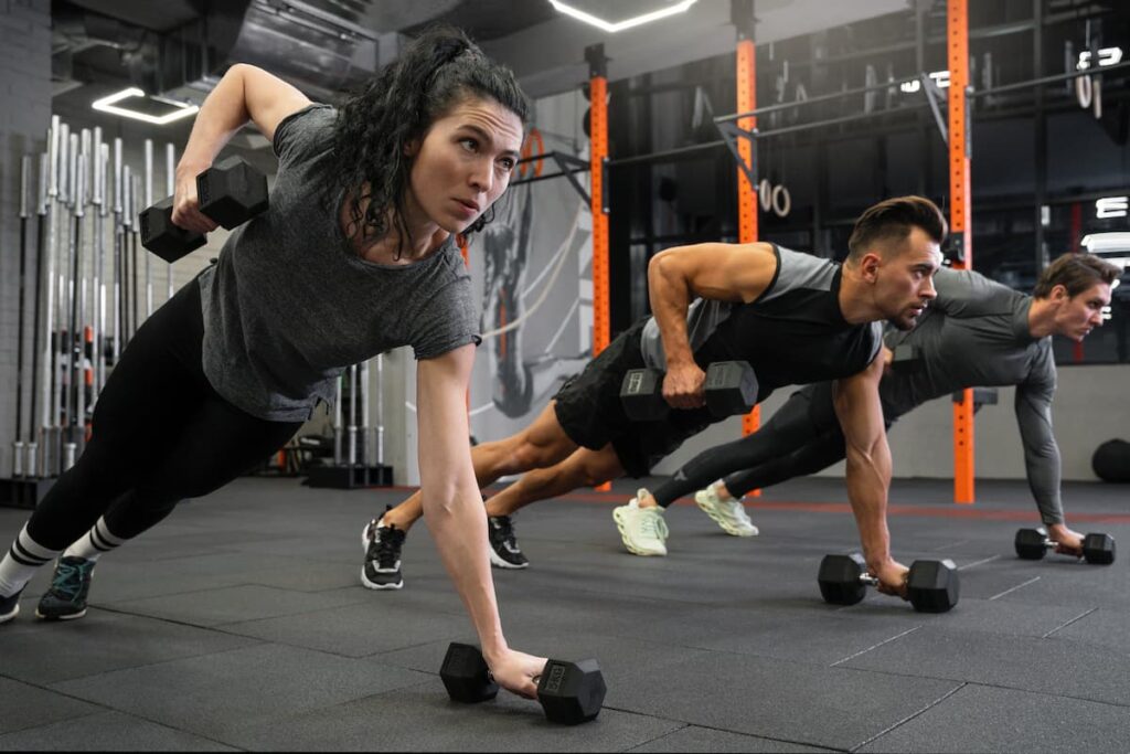 mujer y dos hombre realizando ejercicios en un gimnasio