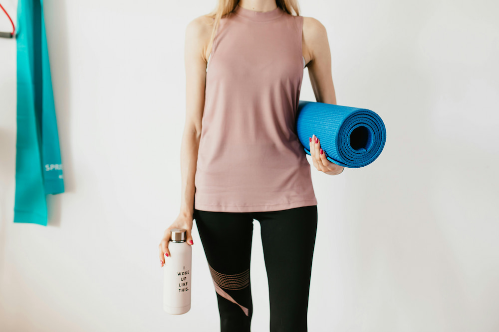 mujer mostrando equipamiento necesario para hacer yoga